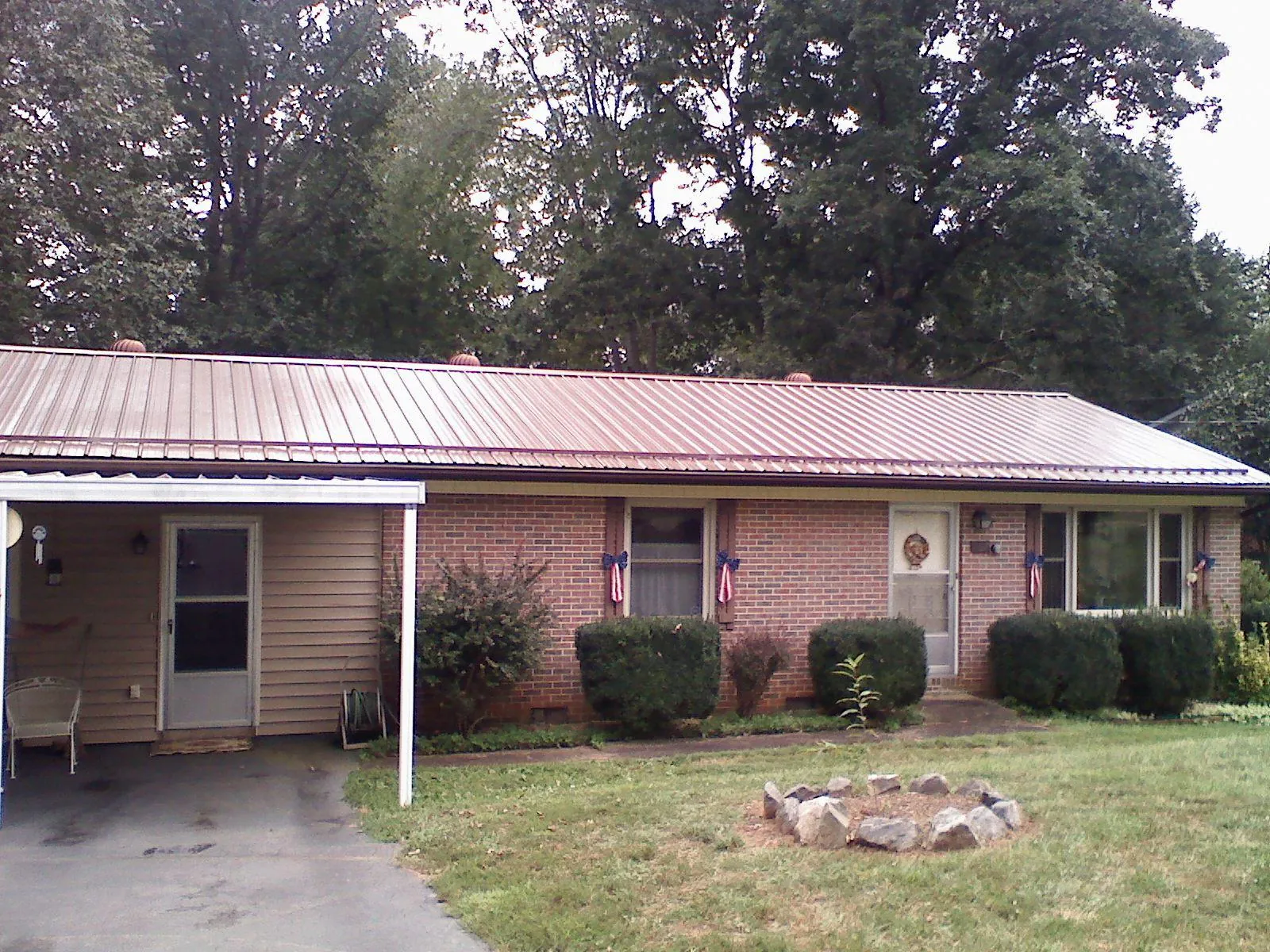 Bronze metal roof and carport on a brick ranch home — Roof Repair work by our crew in Oak City